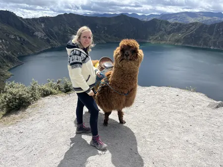Turista junto a una alpaca en la laguna del Quilotoa