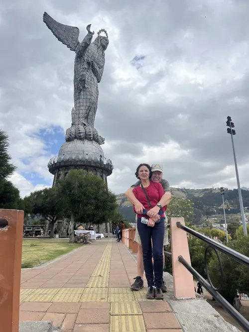 Un hombre abrazando a su esposa con la Virgen del Panecillo al fondo