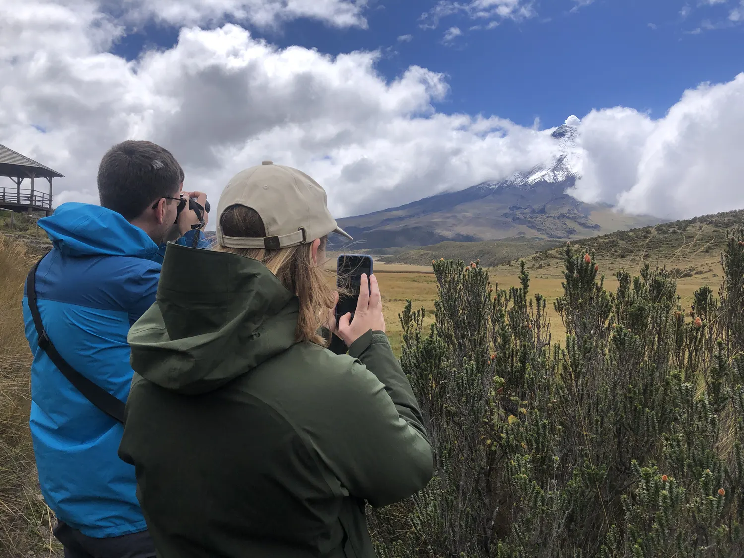 Pareja fotografiando el Cotopaxi con chuquiragua desde Limpiopungo